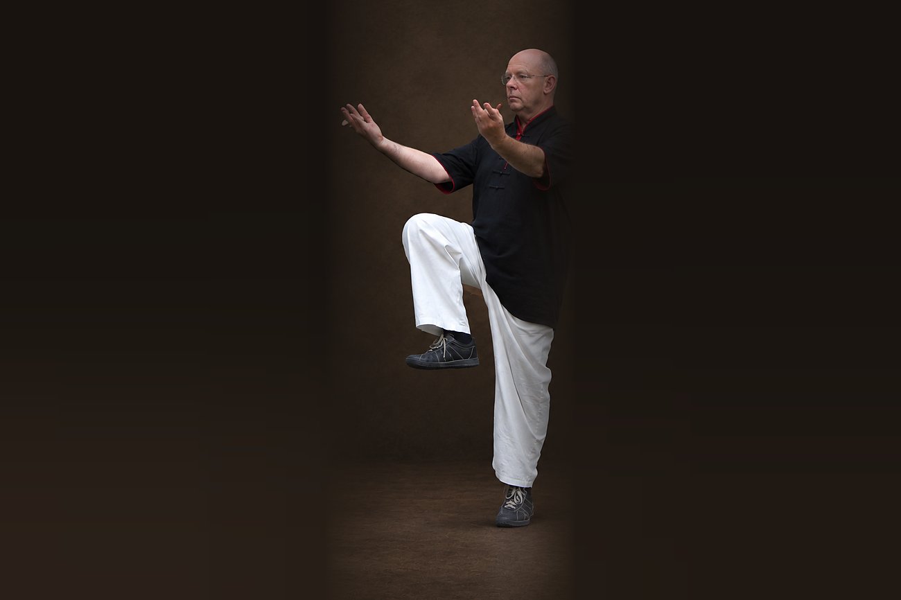 Gleichgewichtsübung im Qi Gong: Horst-Rainer Rust steht auf einem Bein, die Hände vor dem Körper