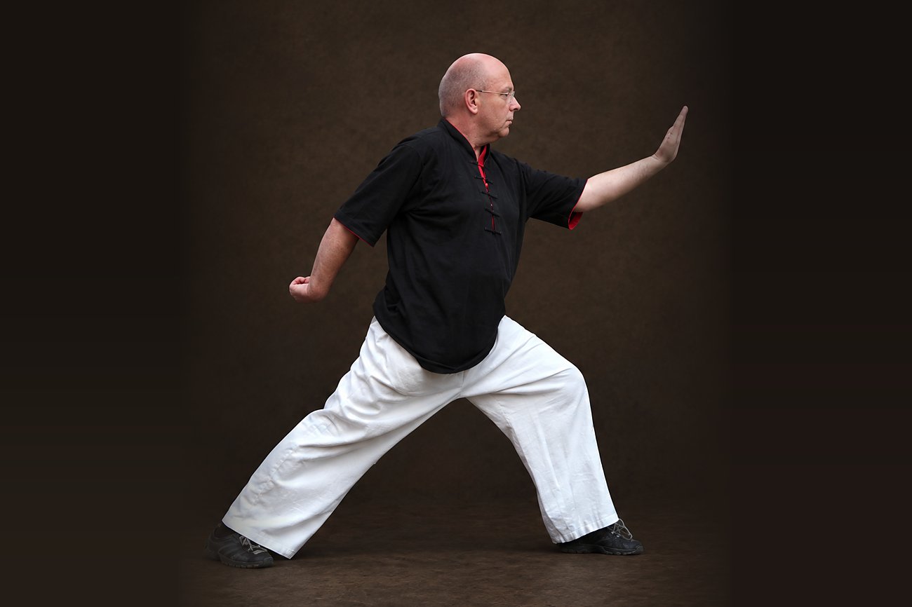 Horst-Rainer Rust im Bogenschritt, eine Handfläche nach vorn geführt – Haltung aus dem Qi Gong
