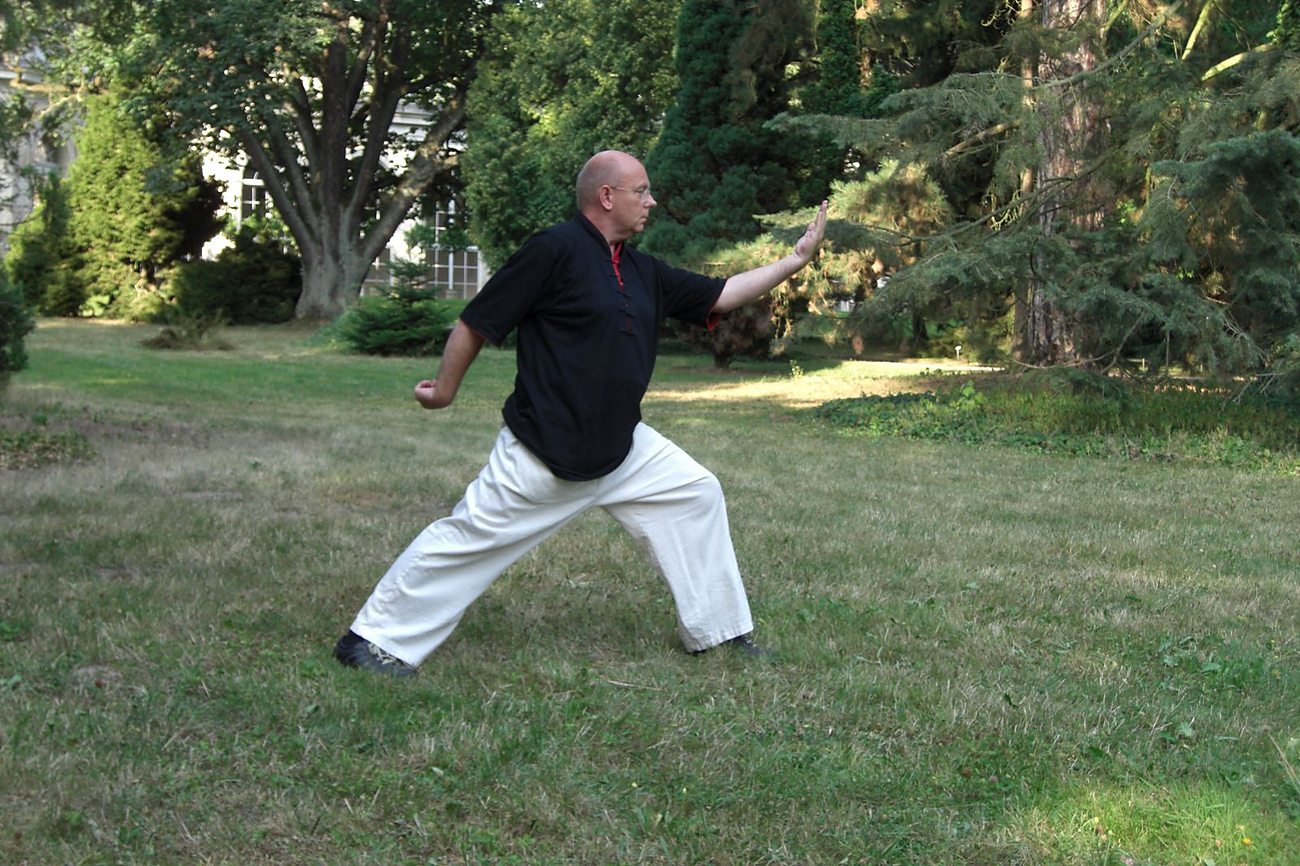 Horst-Rainer Rust übt eine Qi-Gong-Haltung auf einer Wiese