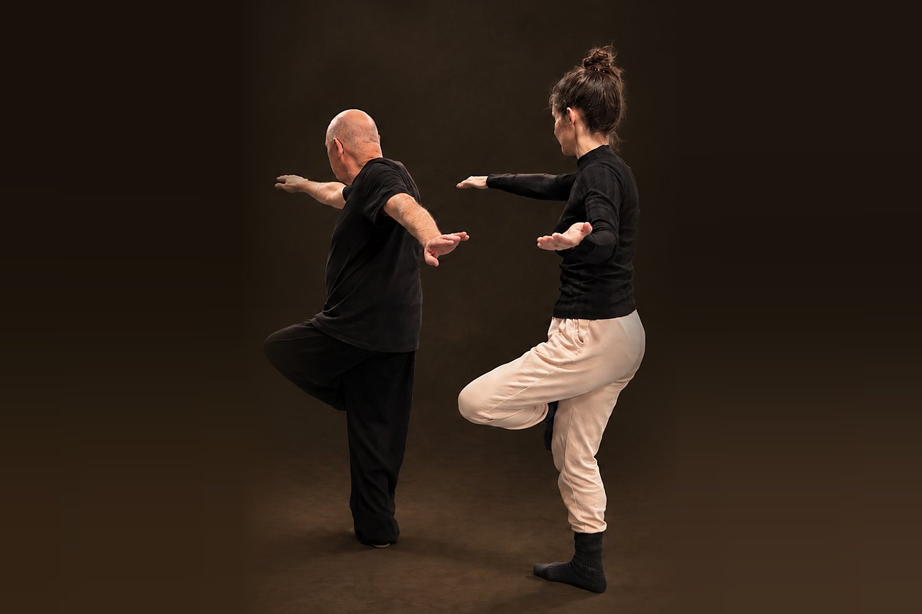 Qi Gong für das Gleichgewicht: zwei Übende stehen auf einem Bein und öffnen die Arme