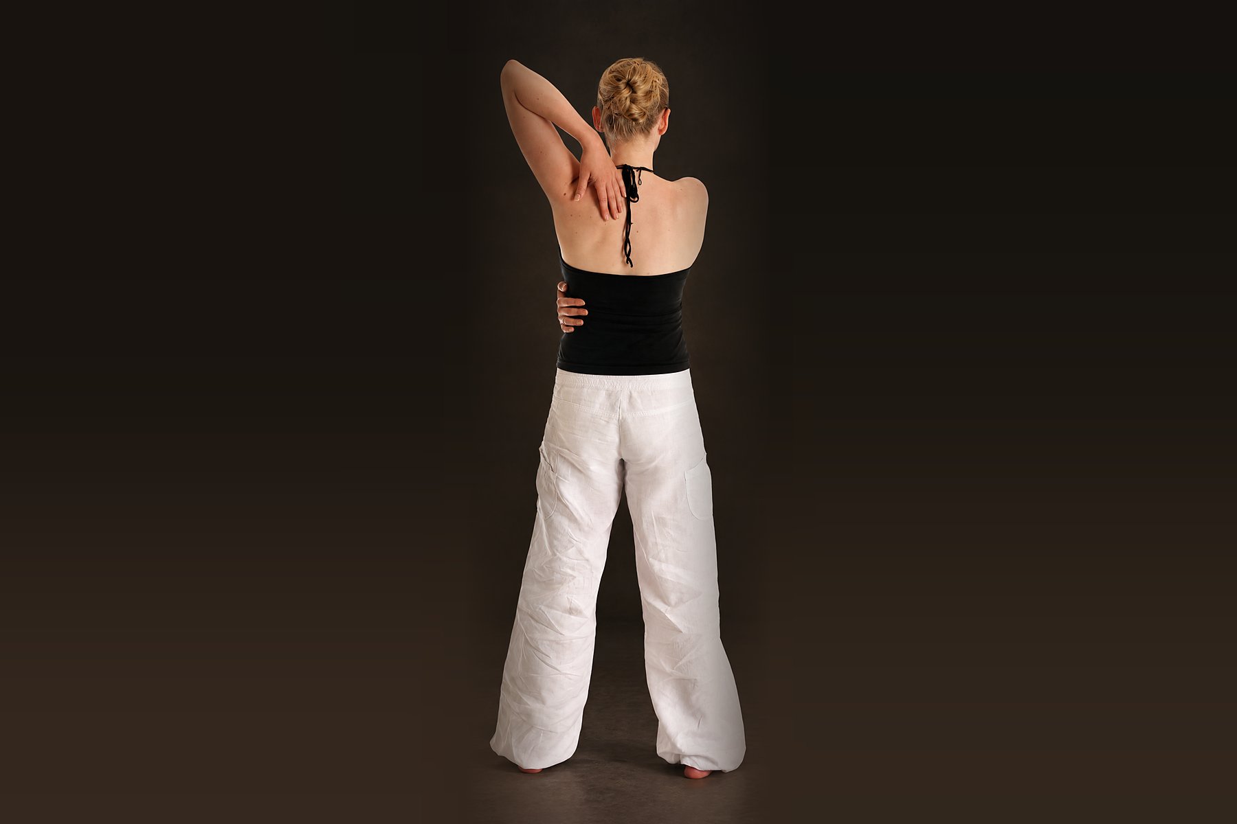 Qi Gong für den Rücken: Übende von hinten, ein Arm über die Schulter geführt, der Rücken lang aufgerichtet