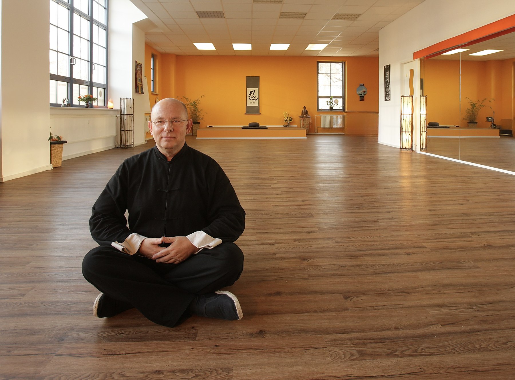 Horst-Rainer Rust sitzt im Schneidersitz im Übungsraum des Qi Gong Vital Zentrums in Radebeul