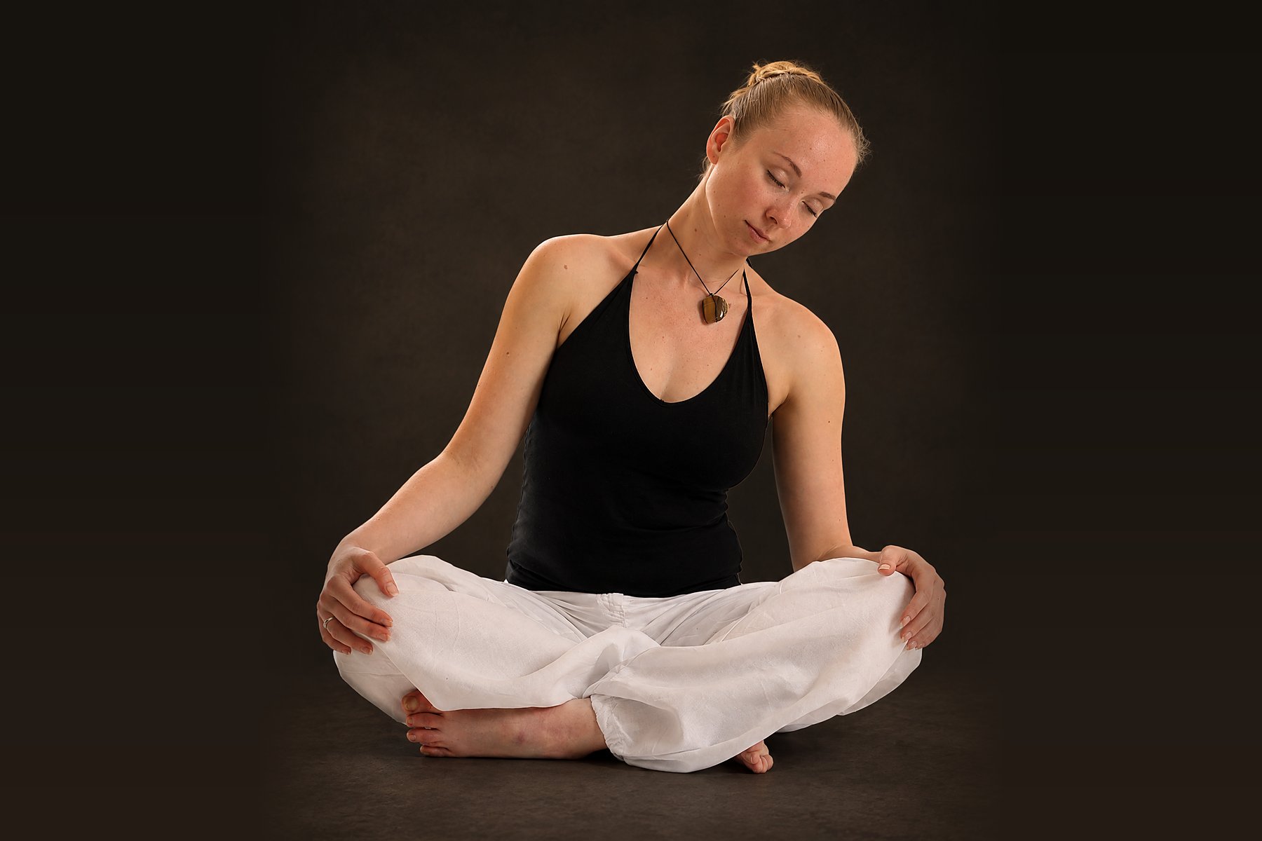Qi Gong im Sitzen: Übende ruhig im Schneidersitz, die Hände auf den Knien